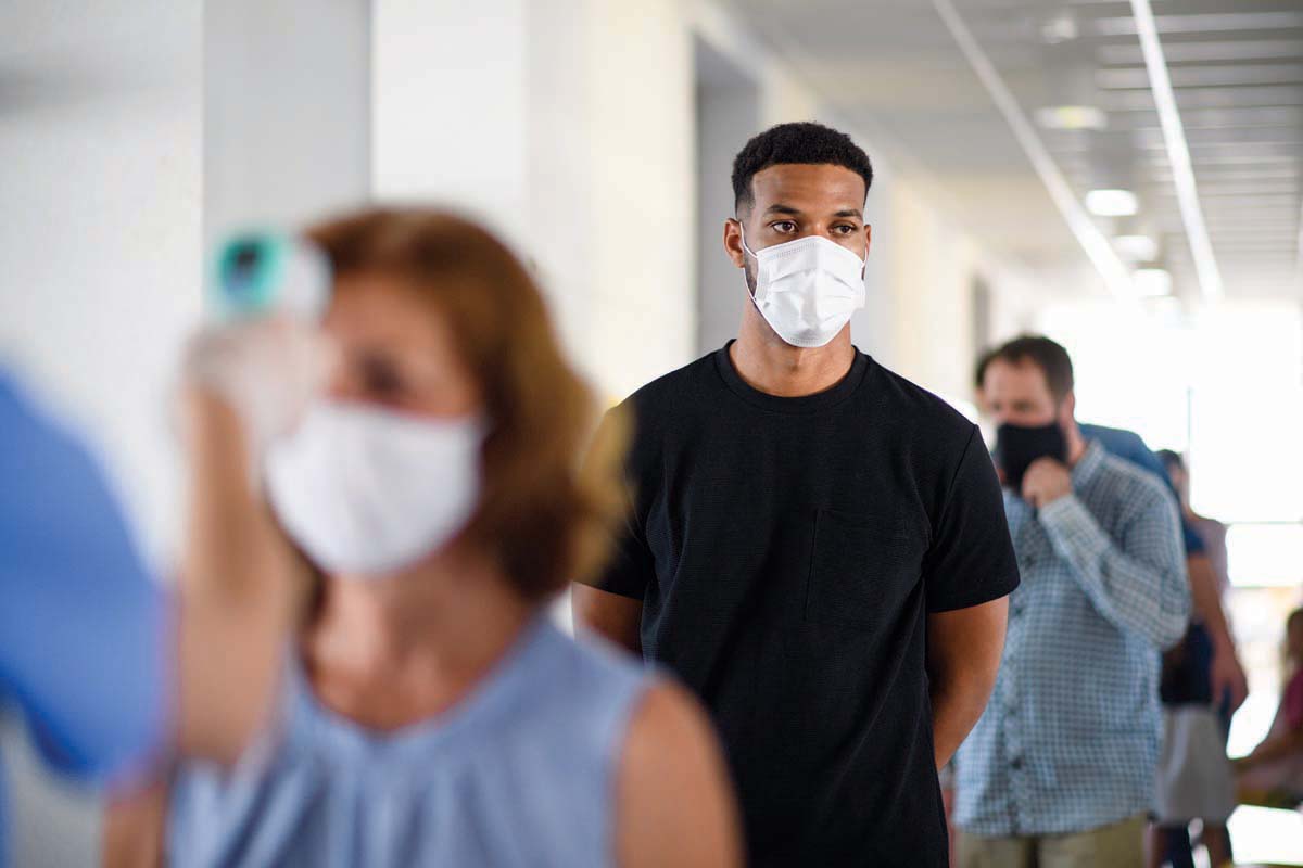 a man wearing a mask stands in line with others