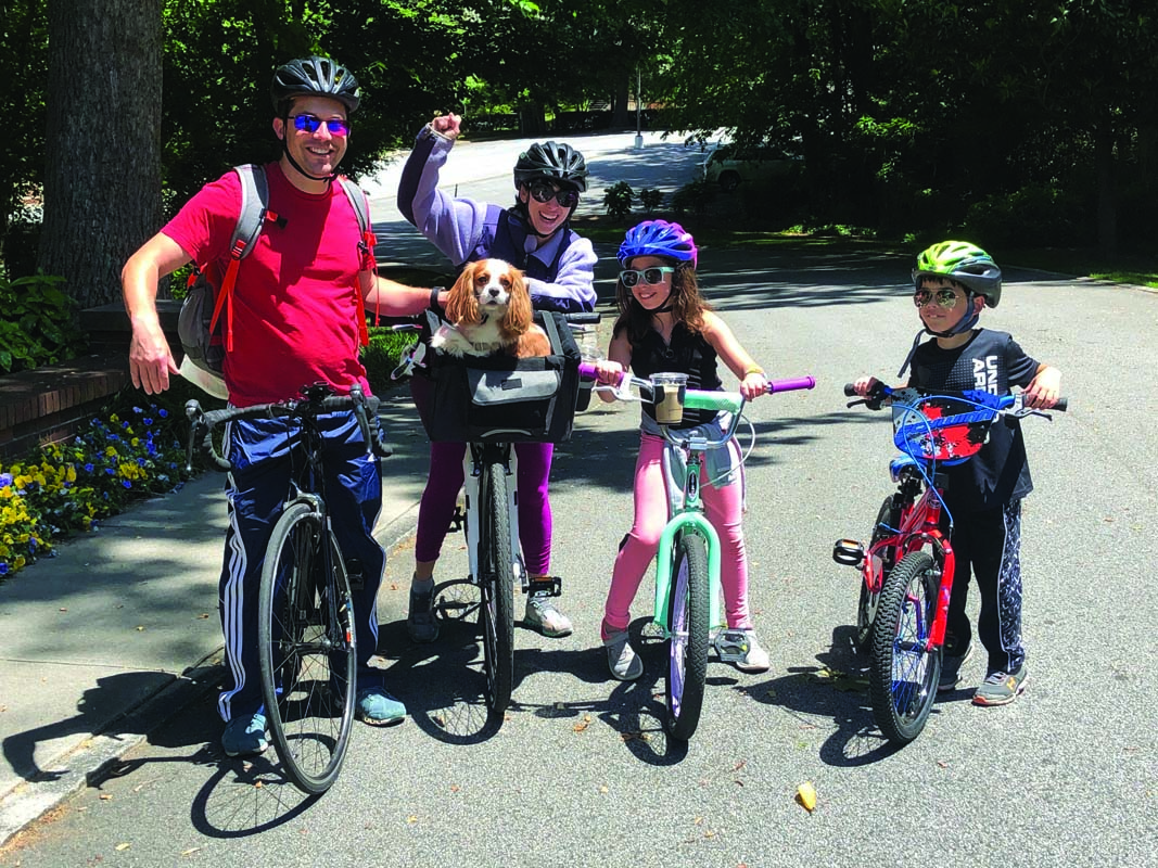 The Siegelman family poses with bicycles and their cocker-spaniel in an outdoor setting.
