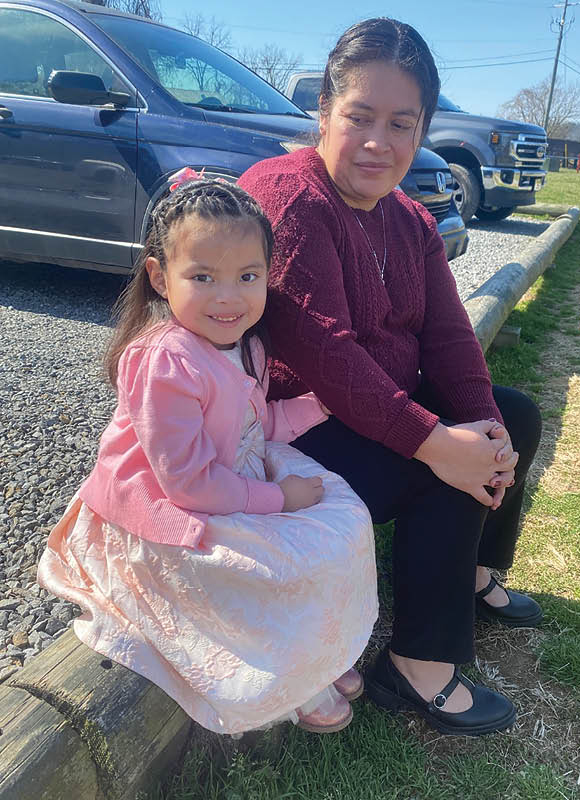 Photo of Scarlett sitting with her mother on the a wall.